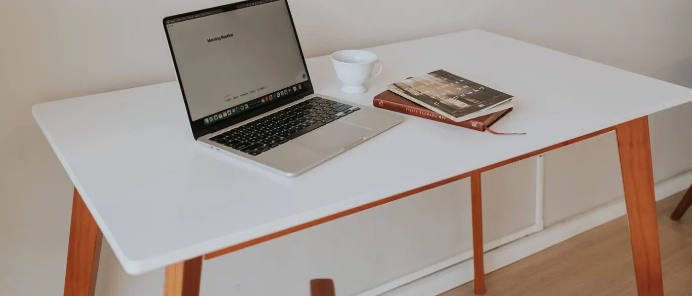 Bureau met laptop en notitieboek bij het raam