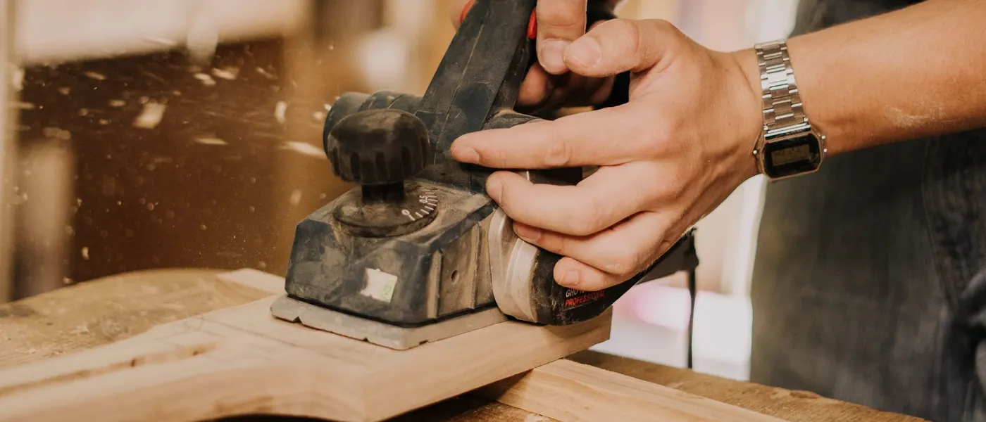 Vakman die een plank bewerkt in zijn atelier